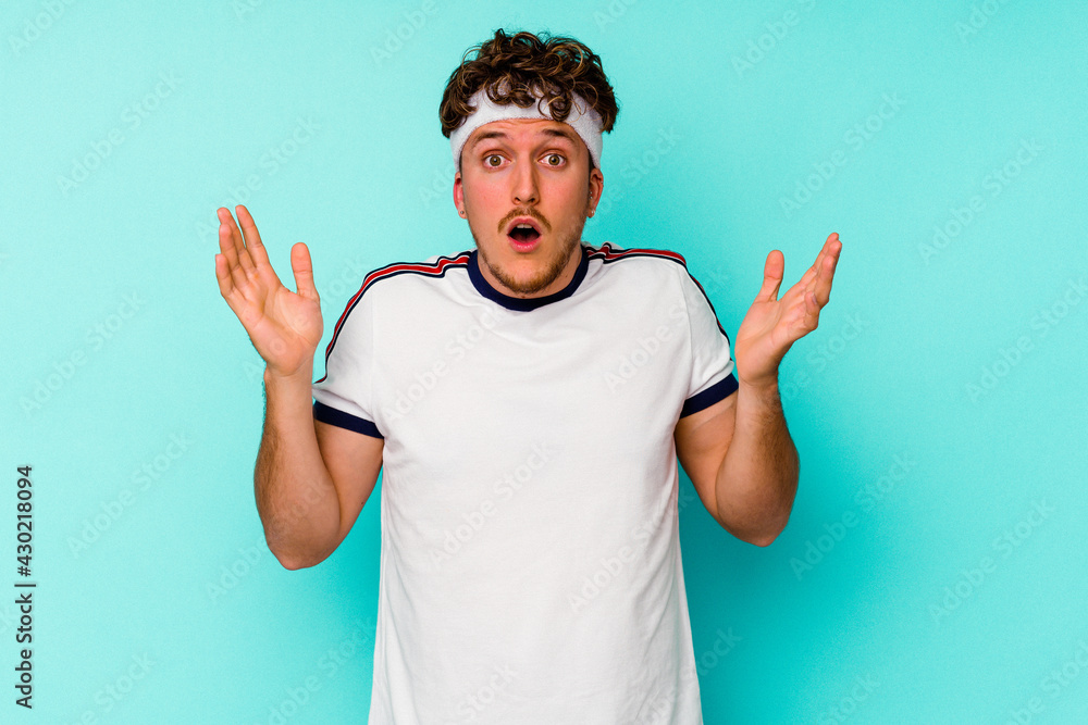 Fototapeta premium Young sport caucasian man isolated on blue background surprised and shocked.