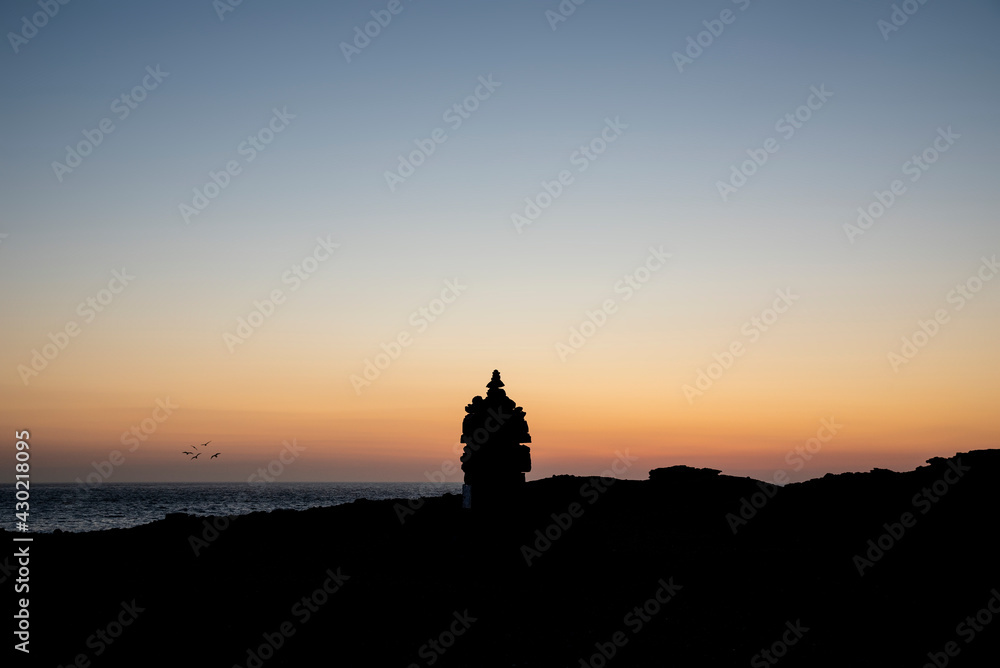 Beautiful silhouette landscape image of zen rock pile against vibrant peaceful sunset