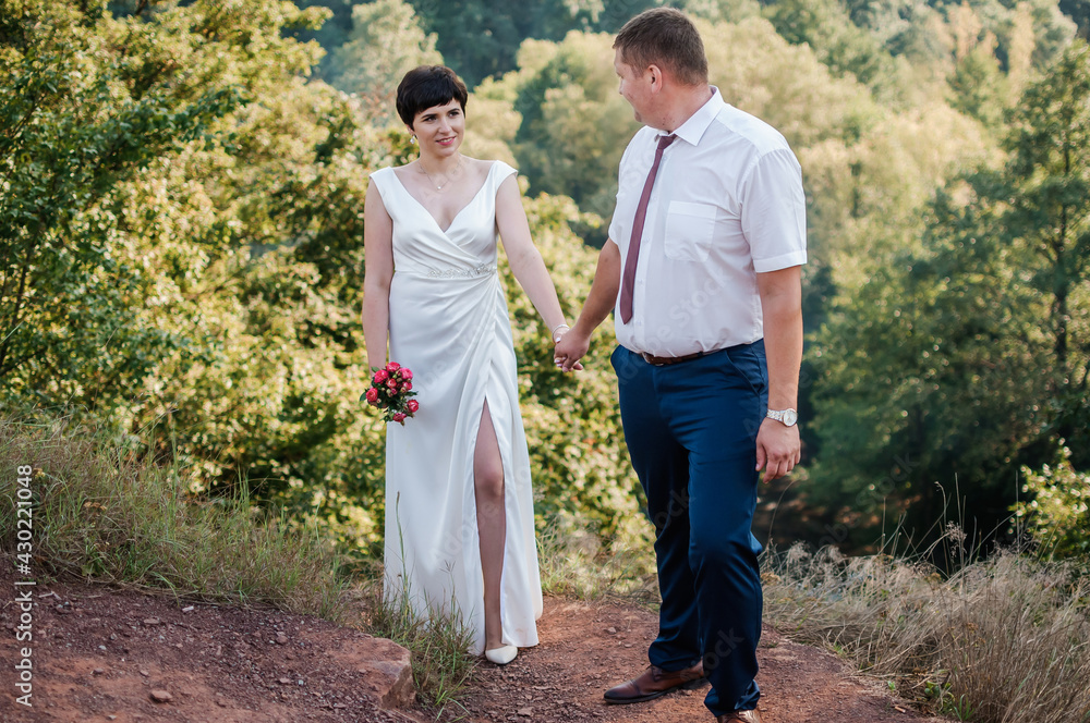 Newlyweds hold hands on the background of the forest Newlyweds hold hands on the background of the forest