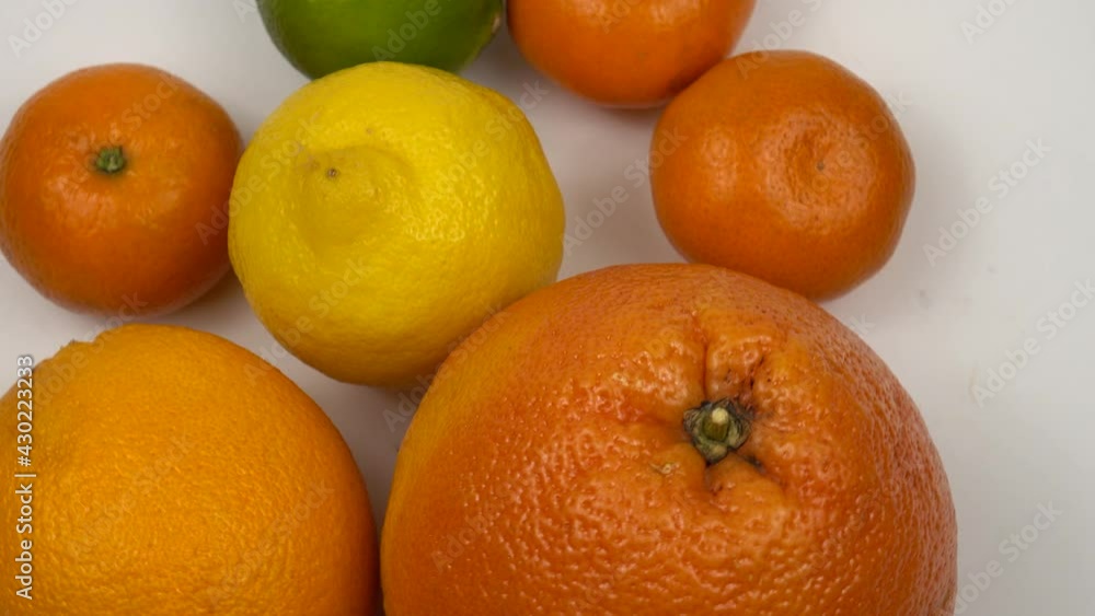 Grapefruits, oranges, tangerines, lemon and lime rotate on a white plate against the white background Grapefruits, oranges, tangerines, lemon and lime rotate on a white plate against the white background