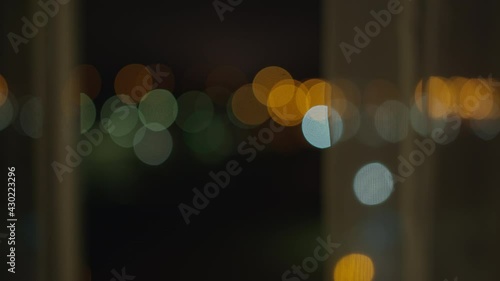 An open window at night, with the tulle blurred city lights