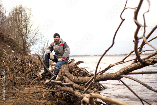 A man sits on a fallen tree on the riverbank, Travel and tourism, selective focus