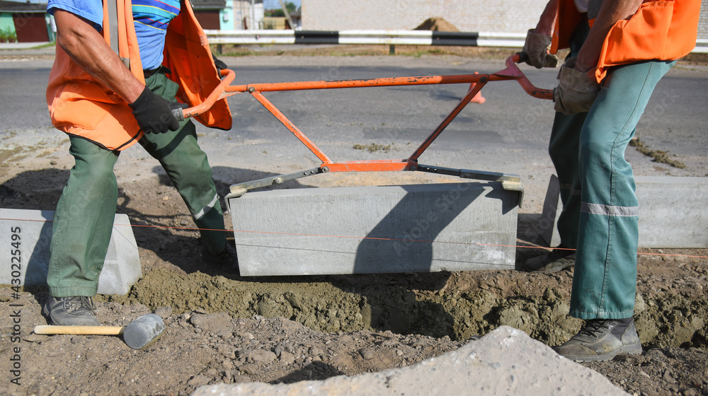 Workers install a curb in concrete, construction of a pedestrian road. Workers install a curb in concrete, construction of a pedestrian road.