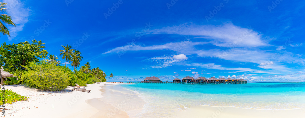 Amazing panorama at Maldives. Luxury resort villas seascape with palm trees, white sand and blue sky. Beautiful summer landscape. Amazing beach background for vacation holiday. Paradise island concept