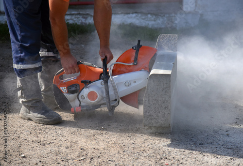 A worker saws a concrete curb with a circular saw.