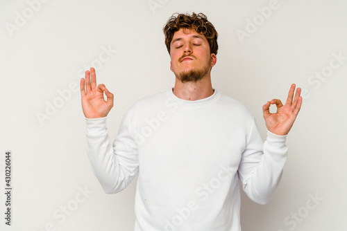 Young caucasian man isolated on white background relaxes after hard working day, she is performing yoga.