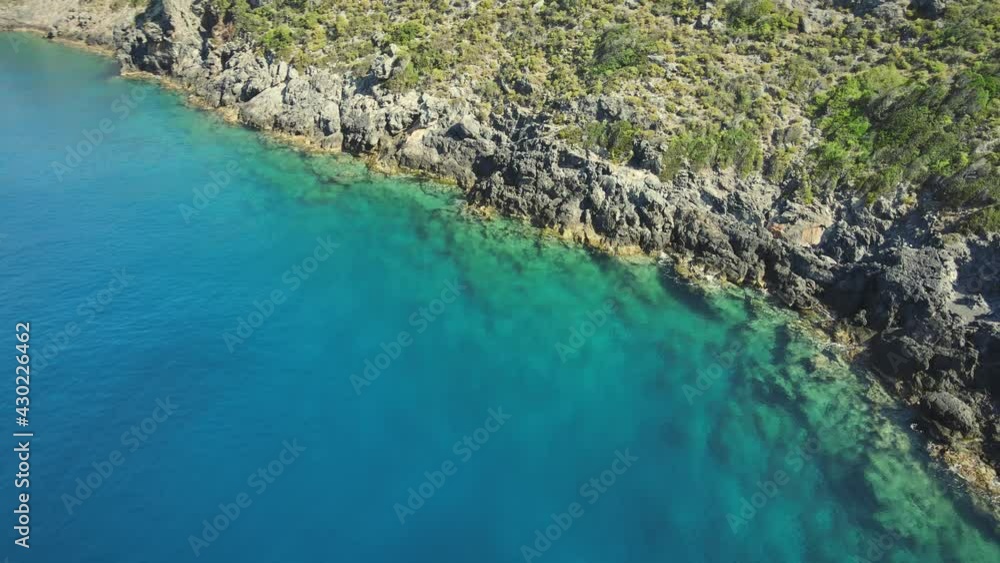 Aerial view of rocky coastline with turquoise and clear sea water surface at sunny day. Summer holiday and travel to sea Aerial view of rocky coastline with turquoise and clear sea water surface at sunny day. Summer holiday and travel to sea