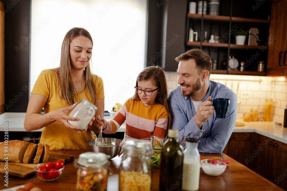 Mom, dad and daughter are cooking in kitchen. Man, young woman and little daughter are making lunch. Mom, dad and daughter are cooking in kitchen. Man, young woman and little daughter are making lunch.