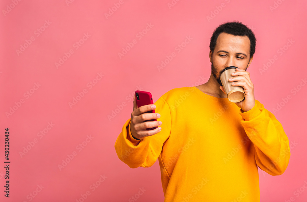 Handsome African American black man using mobile phone and drinking take away coffee cup. Isolated over pink background. Handsome African American black man using mobile phone and drinking take away coffee cup. Isolated over pink background.