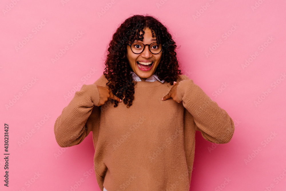 Young mixed race woman isolated on pink background surprised pointing with finger, smiling broadly. Young mixed race woman isolated on pink background surprised pointing with finger, smiling broadly.