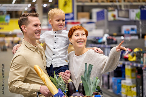 caucasian family with little boy son walking through household appliances section in supermarket aisle