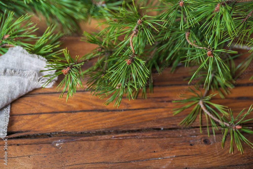 Wooden table with pine branches with green long needles, a fragment of rough gray fabric. Wooden table with pine branches with green long needles, a fragment of rough gray fabric.