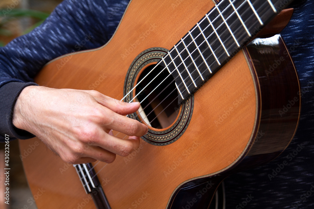 Fototapeta premium young man plays spanish guitar close up