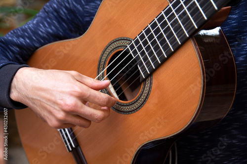 young man plays spanish guitar close up