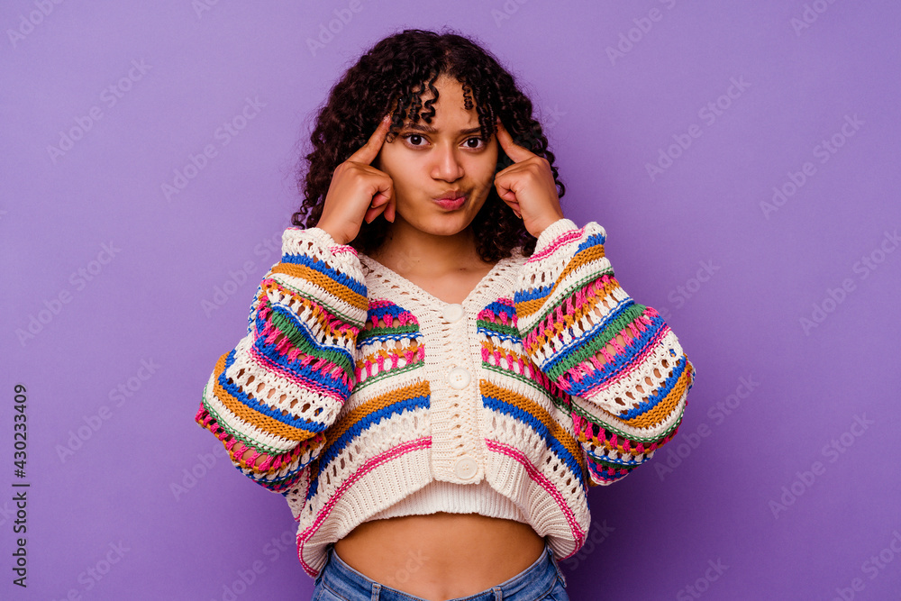 Young mixed race woman isolated on purple background focused on a task, keeping forefingers pointing head. Young mixed race woman isolated on purple background focused on a task, keeping forefingers pointing head.