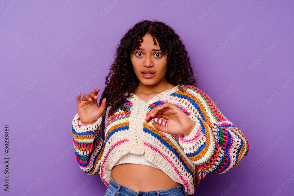 Young mixed race woman isolated on purple background being shocked due to an imminent danger