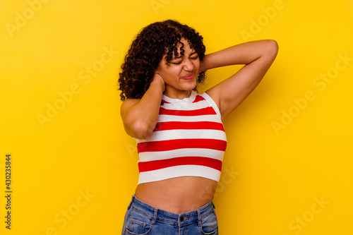 Young mixed race woman isolated on yellow background suffering neck pain due to sedentary lifestyle.