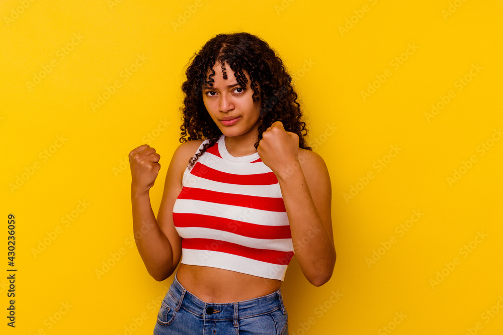 Young mixed race woman isolated on yellow background showing fist to camera, aggressive facial expression. Young mixed race woman isolated on yellow background showing fist to camera, aggressive facial expression.