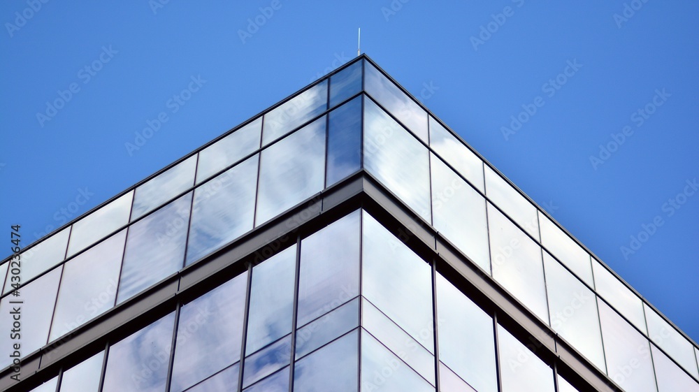Modern office building detail, glass surface on a clear sky background. Transparent glass wall of office building. Modern office building detail, glass surface on a clear sky background. Transparent glass wall of office building.
