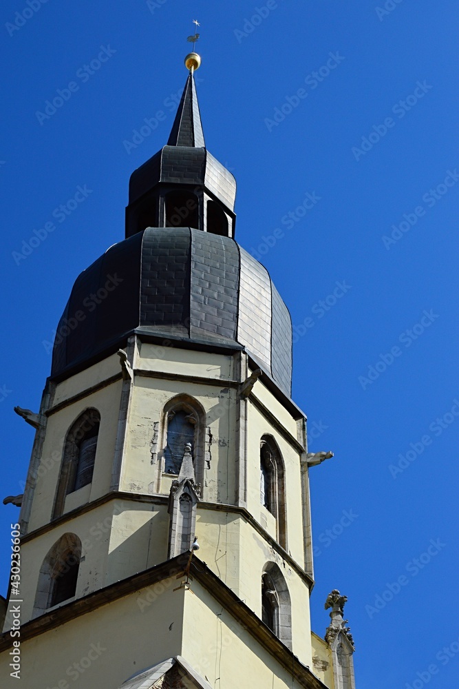 Right, southern gothic church tower of Cathedral of Saint Nicholas on Square Of Saint Nicholas in Trnava, Slovakia, sunbathing in spring sunshine, blue skies.