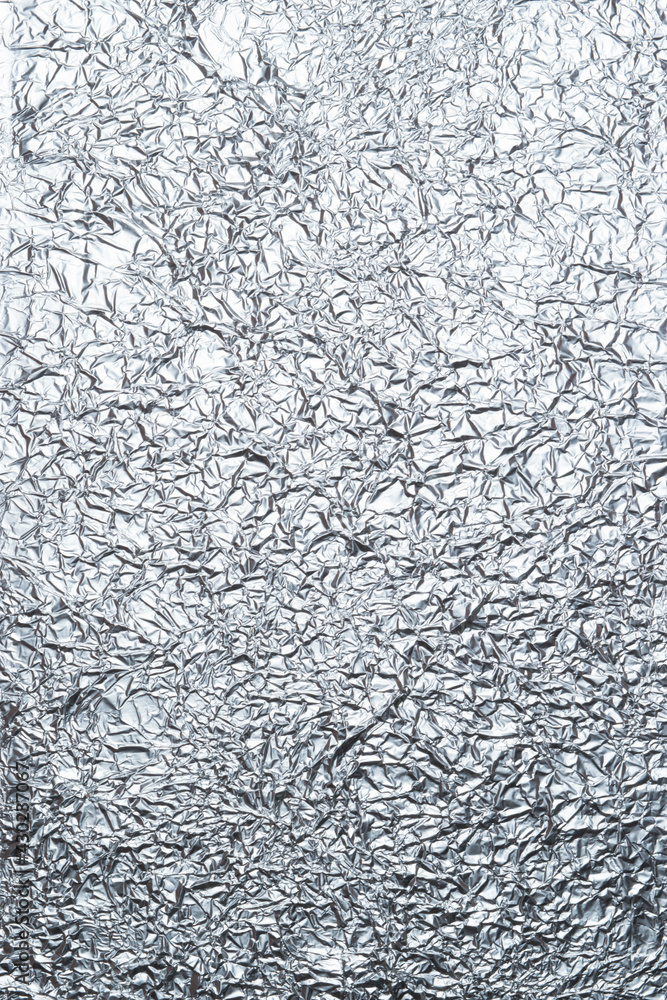 Crumpled shiny metal foil texture or background for design. Gradient, cool shades. Abstract drawing on a thin sheet of aluminum foil. Vertical photo Crumpled shiny metal foil texture or background for design. Gradient, cool shades. Abstract drawing on a thin sheet of aluminum foil. Vertical photo