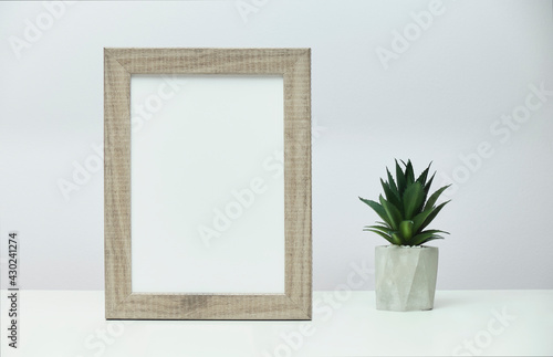 White marble desk with vertical photo frame and a little cactus in concrete flower pot near a gray wall. © Alejandro