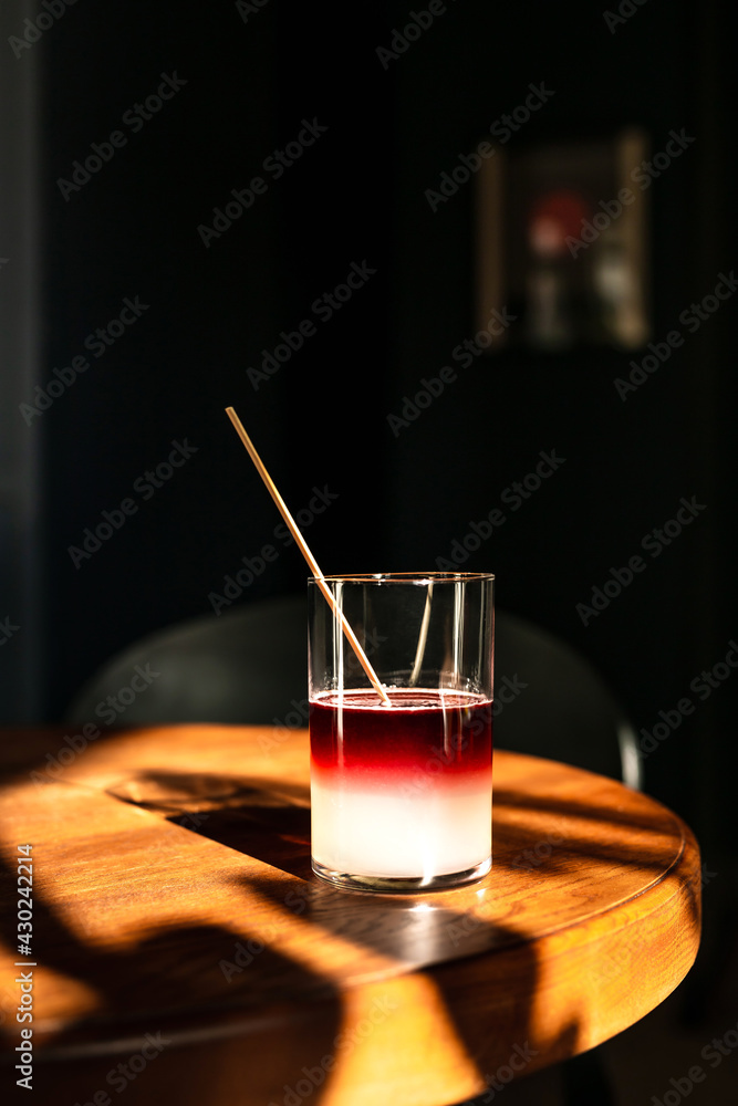 A sweet and sour refreshing blackberry gin bramble cocktail in a highball glass without ice in direct hard sunlight with long shadows, on a wooden table, vertical photo with copy space A sweet and sour refreshing blackberry gin bramble cocktail in a highball glass without ice in direct hard sunlight with long shadows, on a wooden table, vertical photo with copy space