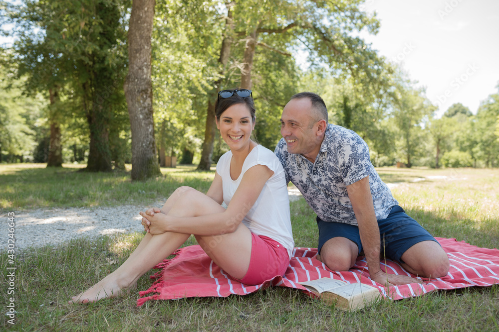 couple sitting outdoors with picnic smiling couple sitting outdoors with picnic smiling