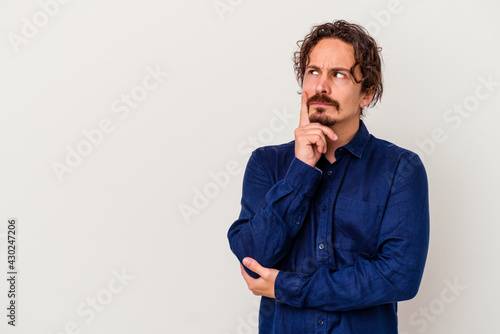 Young caucasian man isolated on white background looking sideways with doubtful and skeptical expression. © Asier