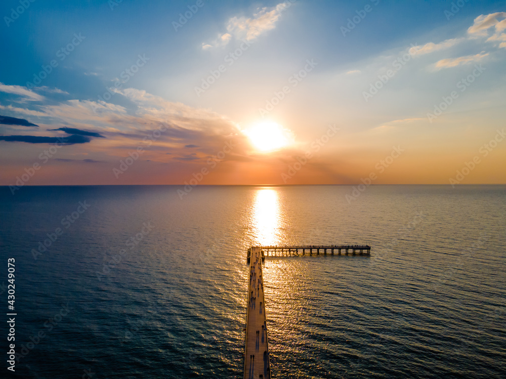 Aerial view of a bridge to sea and a sunset in horizon