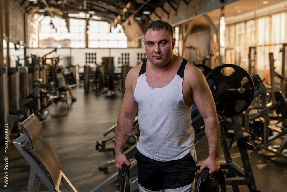 Fototapeta premium novice athlete adult man in the gym holding pancakes for the simulator