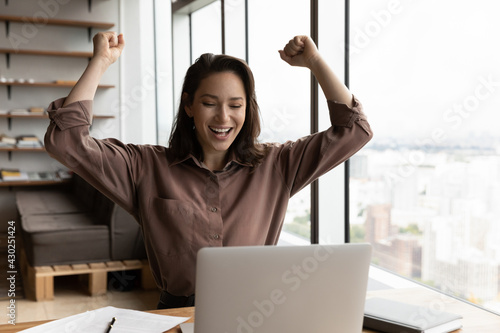 Obraz na plátně Overjoyed young Caucasian female employee look at laptop screen triumph reading good news online