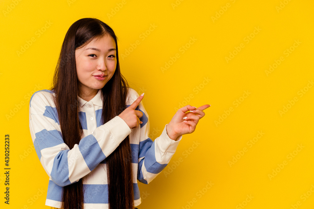 Young chinese woman isolated on yellow background pointing with forefingers to a copy space, expressing excitement and desire. Young chinese woman isolated on yellow background pointing with forefingers to a copy space, expressing excitement and desire.