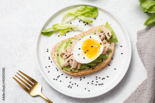 Avocado, canned tuna and boiled egg toast on white stone table background. Healthy food, avocado open sandwich for breakfast or lunch. Flat lay, top view