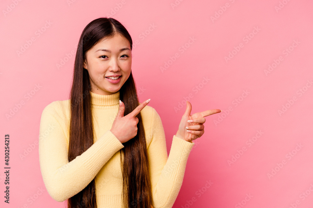Young chinese woman isolated on pink background excited pointing with forefingers away. Young chinese woman isolated on pink background excited pointing with forefingers away.