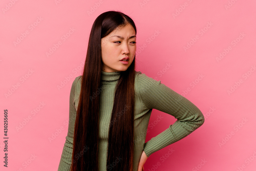 Young chinese woman isolated on pink background suffering a back pain. Young chinese woman isolated on pink background suffering a back pain.