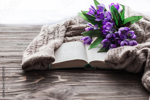 Cozy morning. Opened book and a bouquet of flowers on a wooden background with copy space. Cozy home interior, lifestyle, romantic atmosphere.