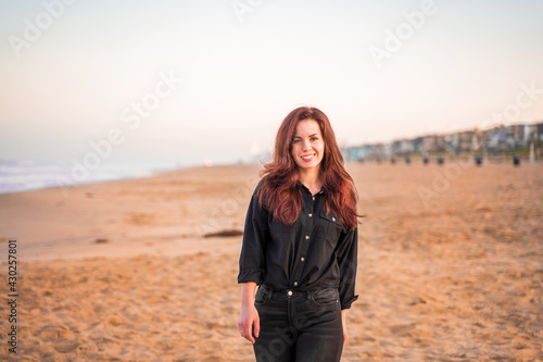 Beautiful young woman with long hair walks on the sand at Manhattan Beach in the early morning, Los Angeles