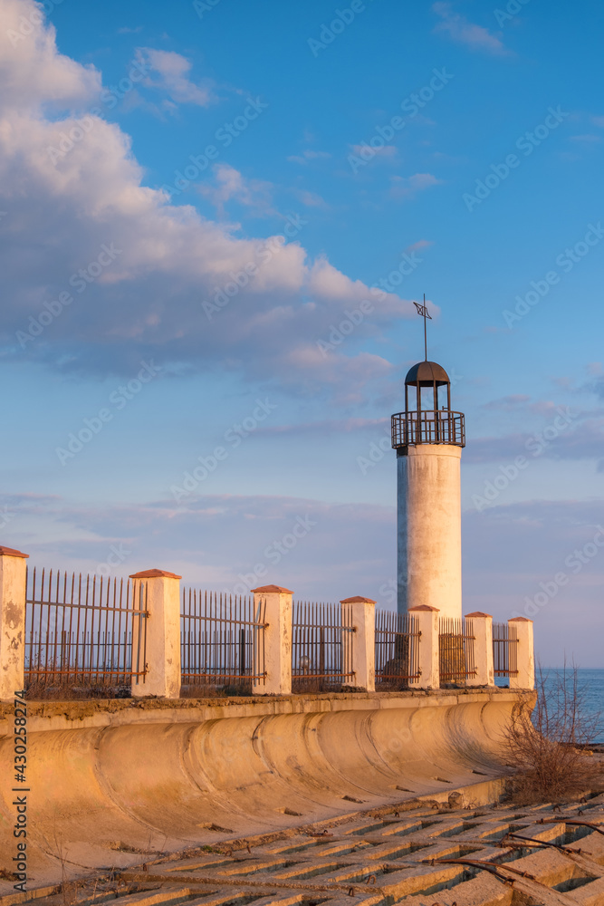 view to lighthouse in sunrise time with soft clouds in sky
