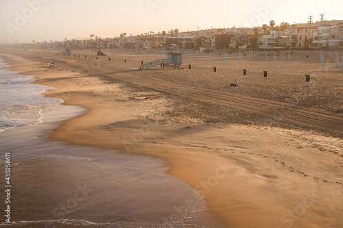 Early morning sunrise and soft haze on Manhattan Beach  waves and rescue towers  Los Angeles
