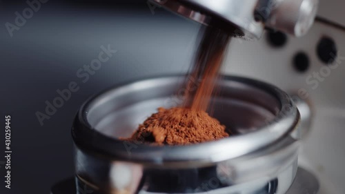 Professional barista worker use grinder machine to grind fresh coffee beans for make hot beverage at coffee cafe shop. Extreme macro close up