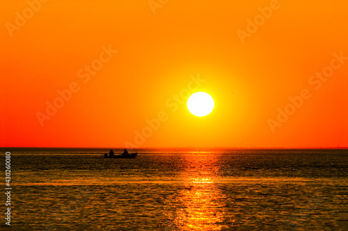 setting sun over the sea with reflection in the water and a sailing boat