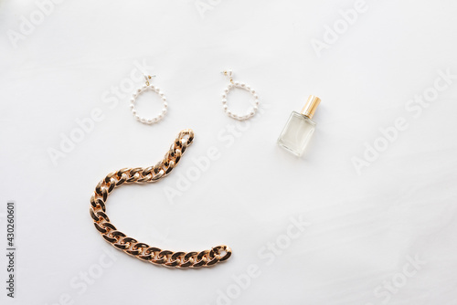 White and gold jewelry collection: chain, pearl earrings, hairpin, perfume. Jewelry for a woman. High quality photo