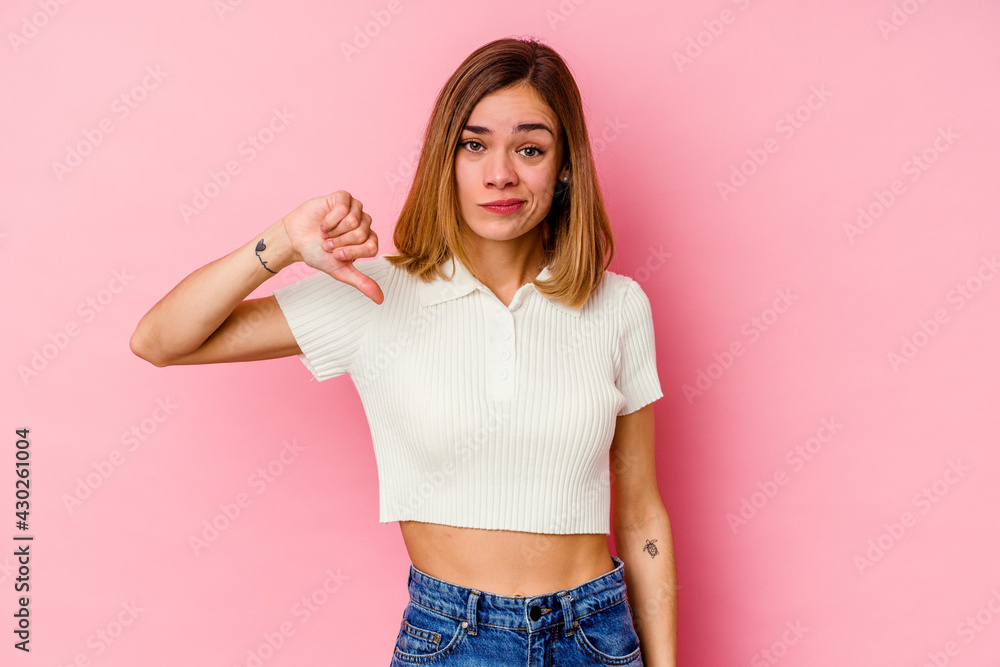 Young caucasian woman isolated on pink background showing thumb down, disappointment concept. Young caucasian woman isolated on pink background showing thumb down, disappointment concept.
