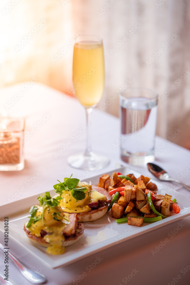 eggs benedict and a mimosa served at a fine dining restaurant during brunch