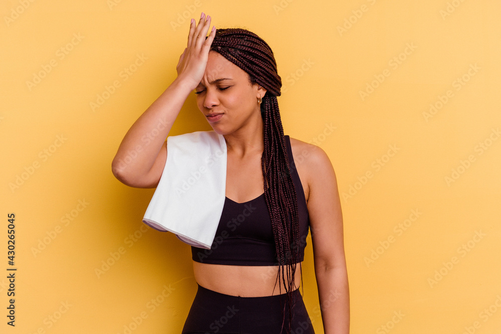 Young sport african american woman holding a towel isolated on yellow background forgetting something, slapping forehead with palm and closing eyes. Young sport african american woman holding a towel isolated on yellow background forgetting something, slapping forehead with palm and closing eyes.