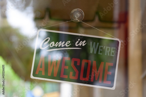 фотографія Close-up on an open sign in the window of a shop saying Come in, we're awesome