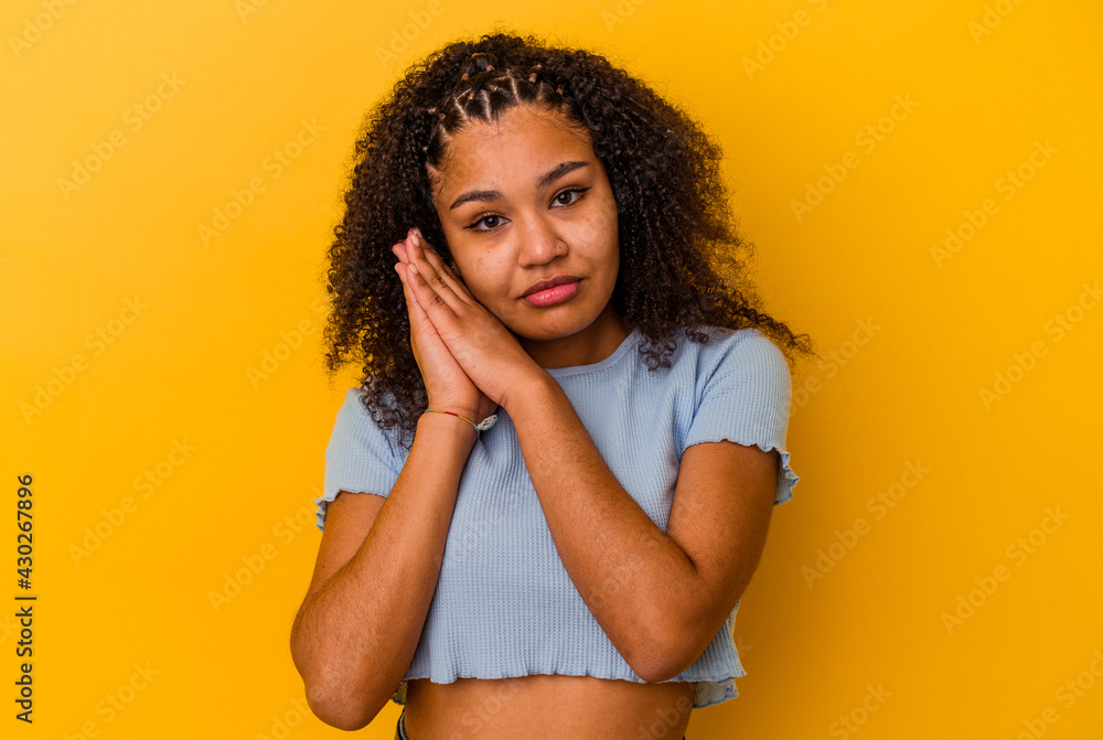 Young african american woman isolated on yellow background yawning showing a tired gesture covering mouth with hand. Young african american woman isolated on yellow background yawning showing a tired gesture covering mouth with hand.