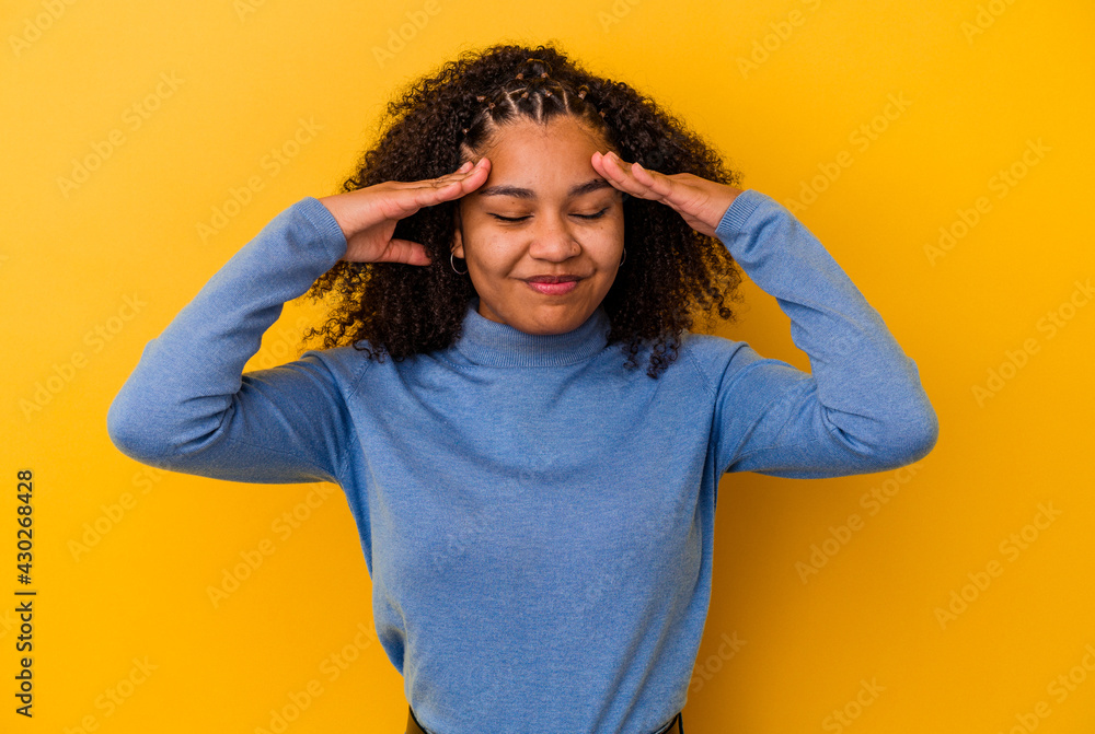 Young african american woman isolated on yellow background having a head ache, touching front of the face. Young african american woman isolated on yellow background having a head ache, touching front of the face.