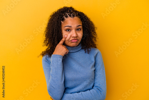 Young african american woman isolated on yellow background crying, unhappy with something, agony and confusion concept. © Asier